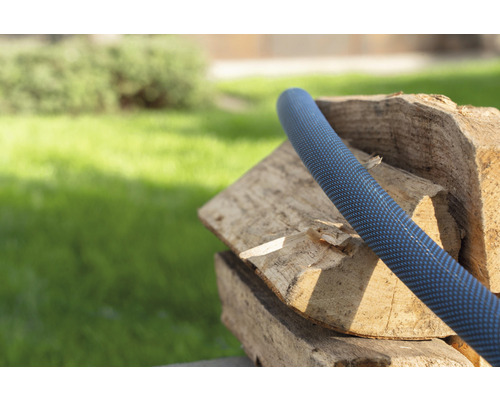 Gartenschlauch auf einem Holzstapel im Garten