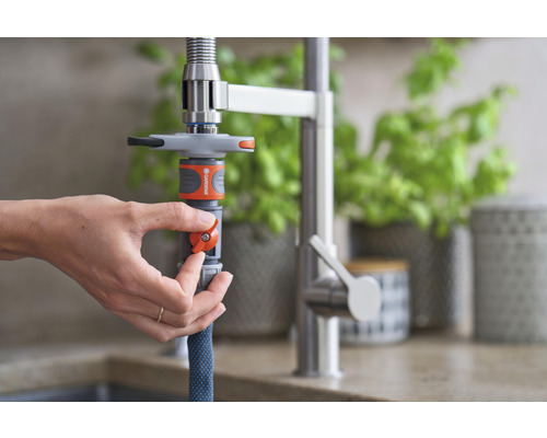 Eine Person befestigt einen Wasserhahnadapter von Gardena an einem Küchenwasserhahn