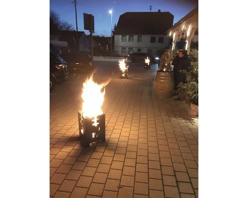 Szene mit mehreren brennenden Feuerschalen auf einem gepflasterten Bereich im Freien