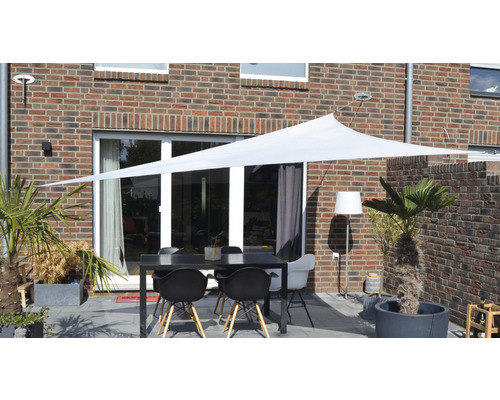Terrasse mit Sonnensegel, Tisch und Stühlen vor einem Backsteinhaus