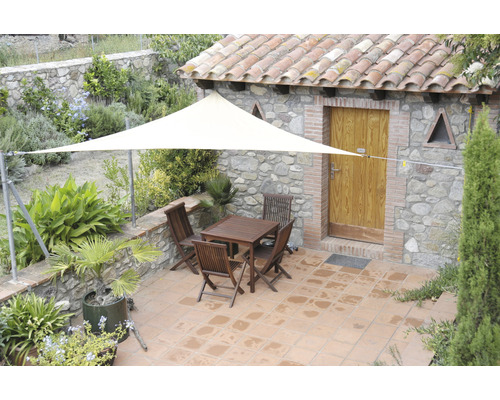 Terrasse mit Sonnensegel, Gartentisch und Stühlen vor Steinhaus