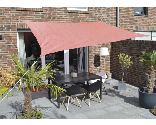 Terrasse mit Sonnensegel, Tisch und Stühlen vor Backsteingebäude