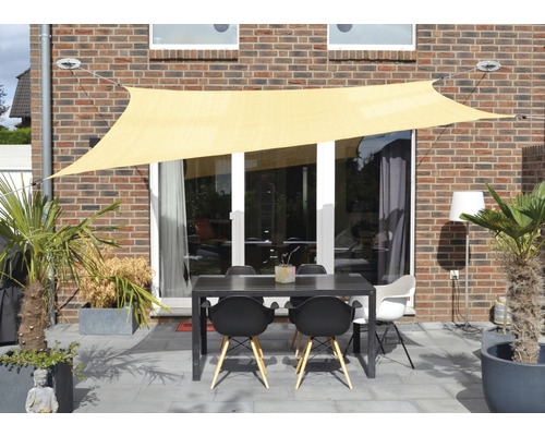 Außenbereich mit Sonnensegel, Tisch und Stühlen auf einer Terrasse vor einem Haus.