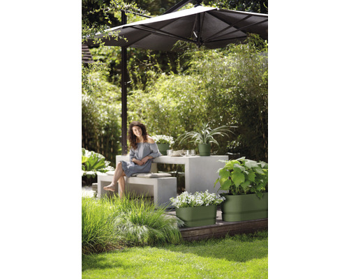 Gartenambiente mit Sonnenschirm, Tisch, Bank und bepflanzten Blumenkästen.