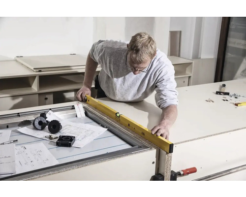 Handwerker mit Wasserwaage an Werkbank