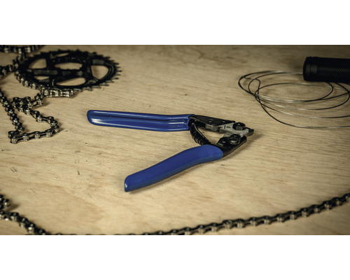 Fahrradwerkzeug mit Kettennieter, Kette, Ritzel und Bremszug auf einem Holztisch