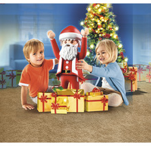 Zwei Kinder mit einer Playmobil-Weihnachtsfigur und Geschenken vor einem Weihnachtsbaum.
