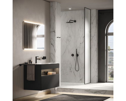Badezimmer mit Waschbecken, beleuchtetem Spiegel und Dusche mit Marmorwand