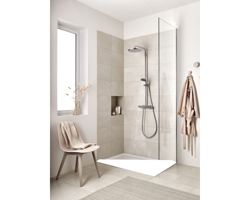 Begehbare Dusche mit Duscharmatur, Duschwanne, Duschwand und Sitzgelegenheit in einem hellen Badezimmer.