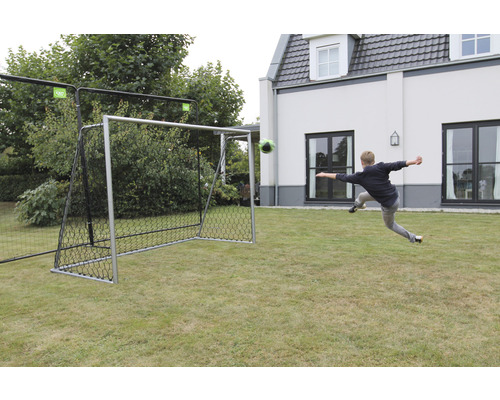 Fussballtor mit Fussball auf Rasen und Person beim Schuss