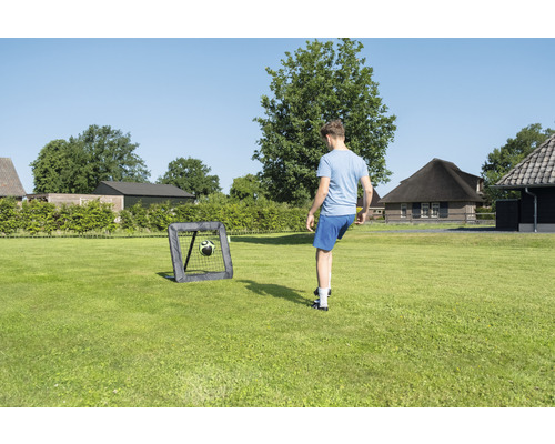 Person spielt Fußball mit einem Fußballtor im Garten.