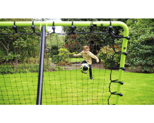 Junge spielt mit einem Ball vor einem Fussballtor im Garten.