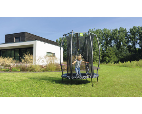 Kind springt auf Gartentrampolin mit Sicherheitsnetz im Garten