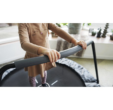 Kind hält sich an einem runden, grauen Kindertrampolin fest