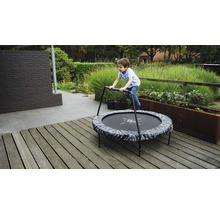 Junge springt auf einem runden Gartentrampolin mit Haltegriff