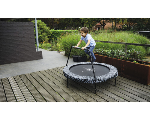Junge springt auf einem runden Gartentrampolin mit Haltegriff