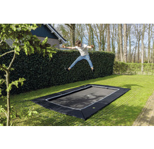 Eingebautes Gartentrampolin mit springendem Jungen im Garten.