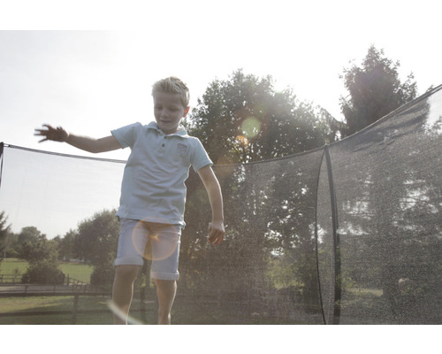 Junge springt auf einem Gartentrampolin mit Sicherheitsnetz