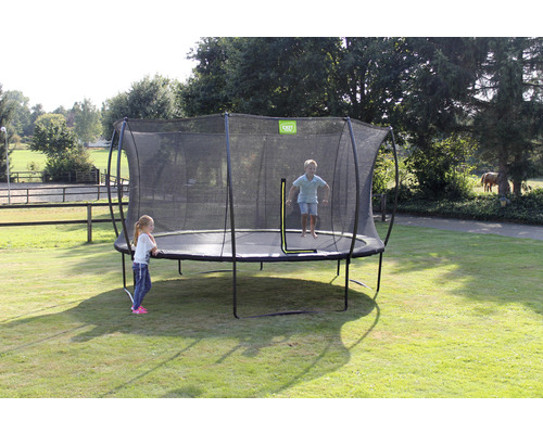 Trampolin mit Sicherheitsnetz im Garten mit spielenden Kindern