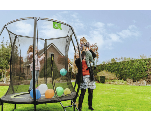 Familie mit einem runden Gartentrampolin mit Sicherheitsnetz auf einer Rasenfläche.