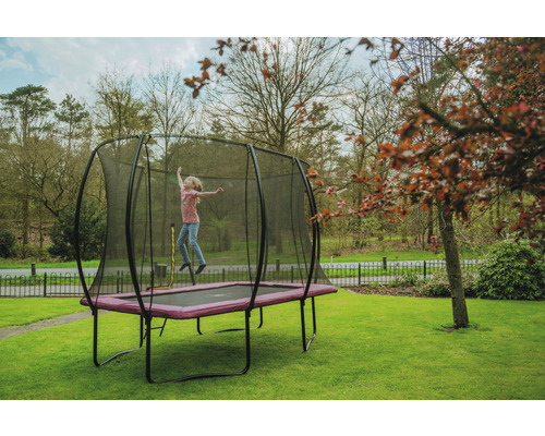 Mädchen springt auf Gartentrampolin mit Sicherheitsnetz