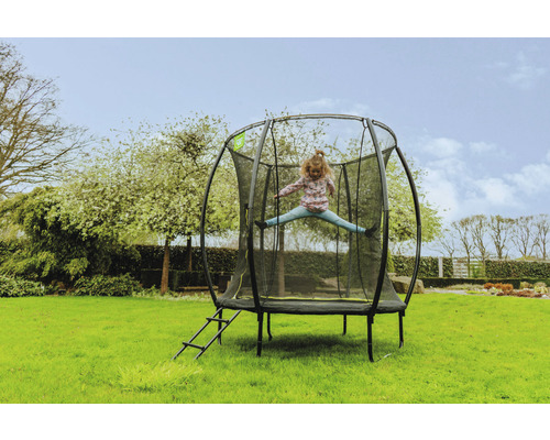 Ein Kind springt auf einem Gartentrampolin mit Sicherheitsnetz und Leiter.