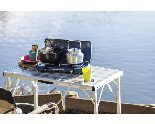 Campingtisch mit Gaskocher, Topf und Kessel am See