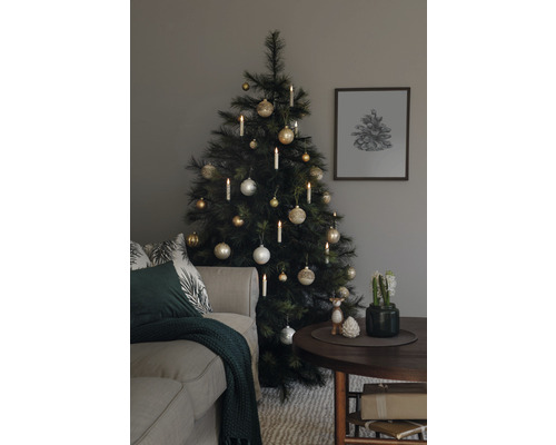 Weihnachtsbaum geschmückt mit Kugeln und Kerzen neben einem Sofa und einem Tisch