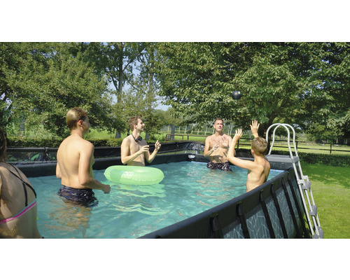 Familie und Freunde spielen im Aufstellpool im Garten.