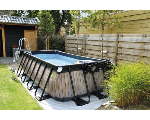 Rechteckiger Pool mit Holzverkleidung, Leiter und Filterpumpe im Garten.