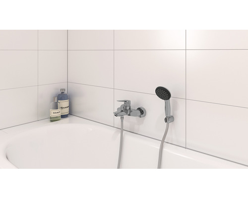 Badezimmer mit Badewanne, Armatur und Handbrause sowie Seife und Shampoo