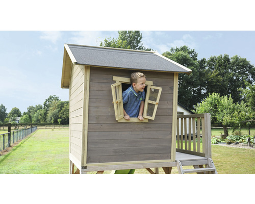 Spielhaus aus Holz mit Jungen am Fenster im Garten