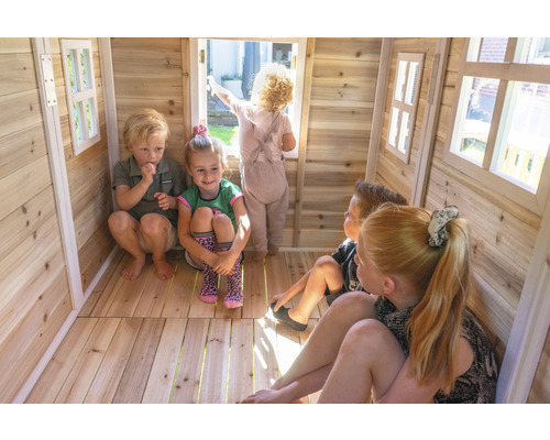 Kinder spielen in einem Holzspielhaus mit Fenstern