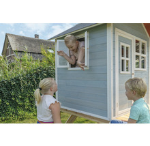 Kind im Holzspielhaus mit Fenstern und Tür im Garten