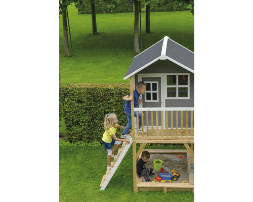 Spielhaus mit Sandkasten und spielenden Kindern im Garten.