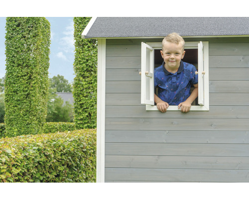 Junge schaut aus dem Fenster eines Spielhauses aus Holz