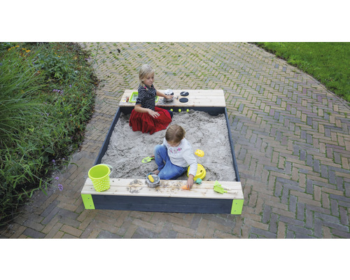 Kinder spielen in einem Sandkasten mit Spielküche im Garten