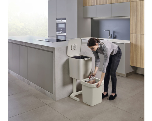 Frau leert Bioabfall in einen Bokashi-Eimer in einer Küche.