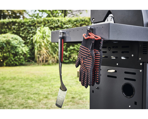 Grillwender und Grillhandschuhe hängen an einem Grill