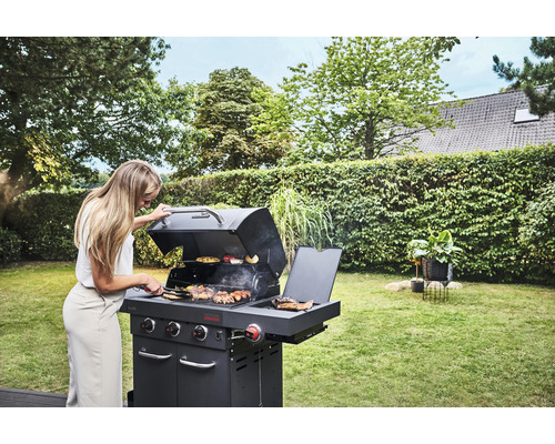 Frau grillt mit einem Holzkohlegrill im Garten.