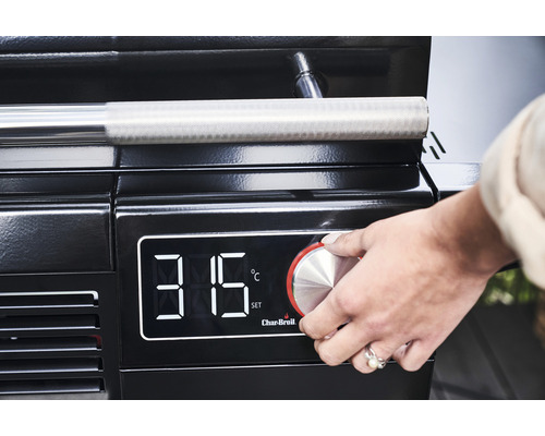 Nahaufnahme eines Grills mit digitaler Temperaturanzeige, an der eine Hand den Regler bedient