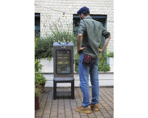 Mann betrachtet elektrischen Räucherofen im Garten.