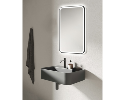 Modernes Badezimmer mit Waschbecken, Armatur, beleuchtetem Spiegel und Handtuch