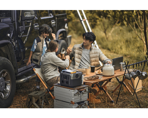 Familiencamping mit tragbarer Powerstation, Tisch und Zubehör neben einem Geländewagen