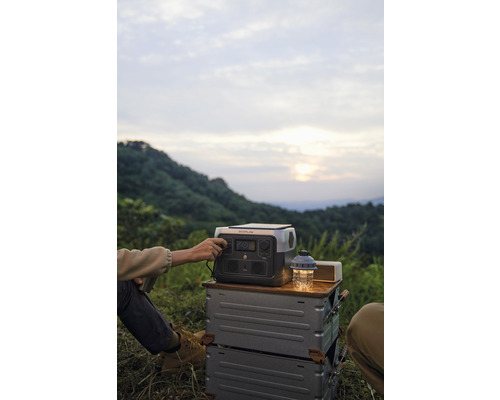 Person bedient tragbare Powerstation auf Campingausflug