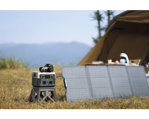Fotografie-Szene im Freien mit Solarmodul, Stromgenerator und Kamera vor einem Zelt