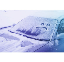 Ein Auto ist mit Schnee bedeckt, auf der Windschutzscheibe ist ein trauriges Gesicht gezeichnet