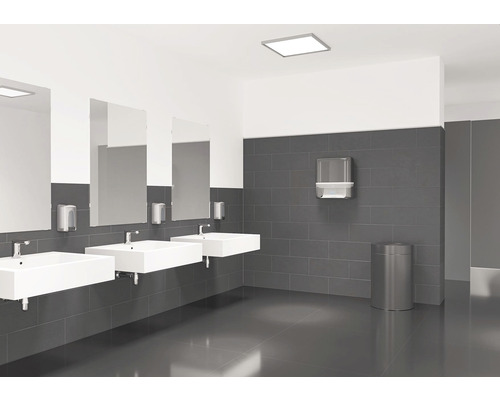 Helles Badezimmer mit drei Waschbecken, Spiegeln, Seifenspendern, Papierhandtuchspender und Abfallbehälter