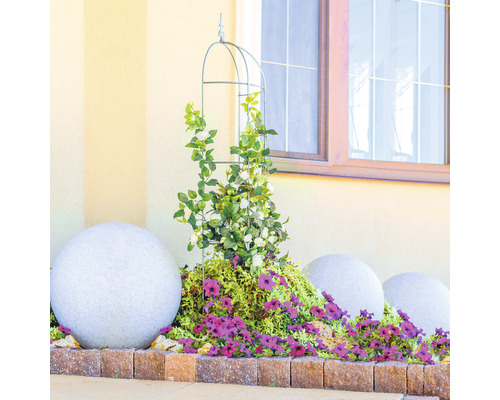 Dekorative Gartenszene mit Rankhilfe, Pflanzen, Blumen und Steinkugeln