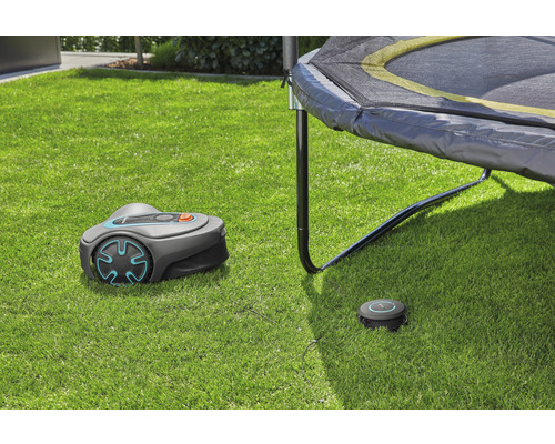 Gardena Mähroboter mit Ladestation auf Rasenfläche unter Trampolin